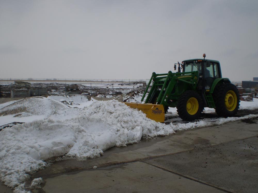 F&W tractor with a loader bucket stacking snow on a commercial lot