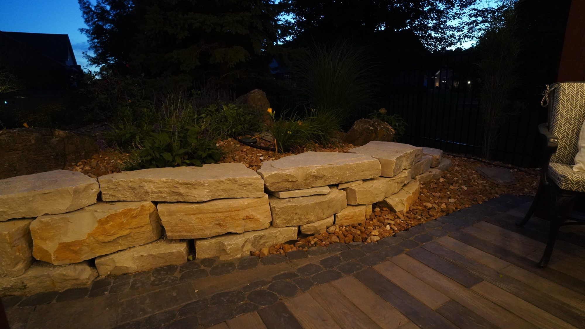 Stacked limestone boulder wall and plantings lit at night