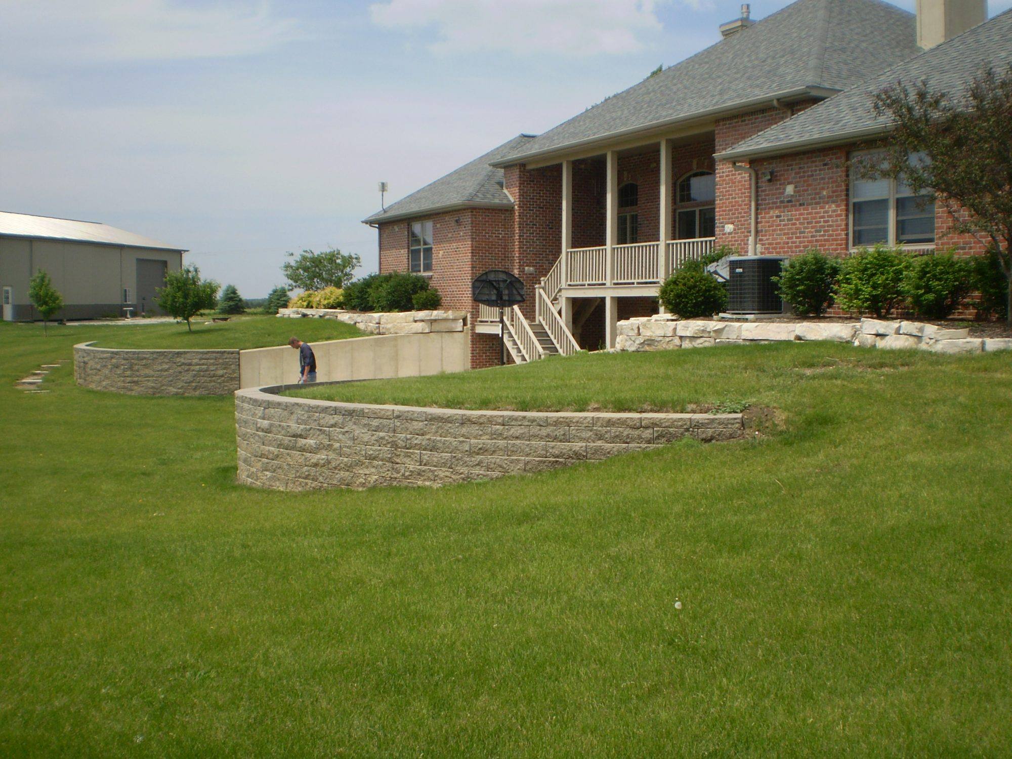 Terraced block retaining walls holding a sloped backyard below a brick home